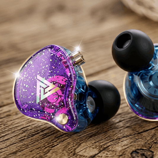 QKZ AK6 Pro in-ear monitors with purple glitter housing and black silicone ear tips on a wooden surface.