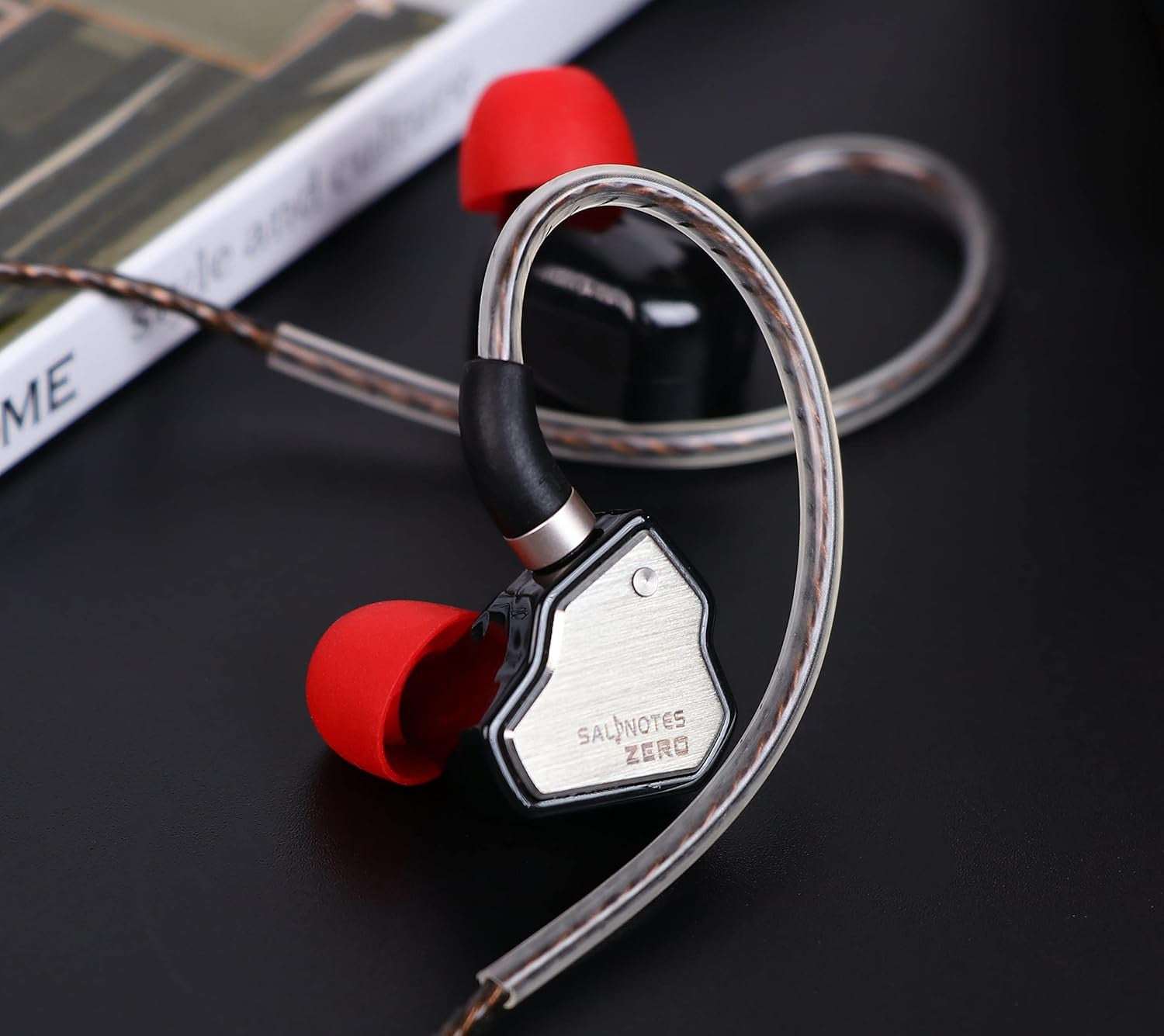Salnotes Zero earphones with metallic casing and red silicone ear tips on a black surface.