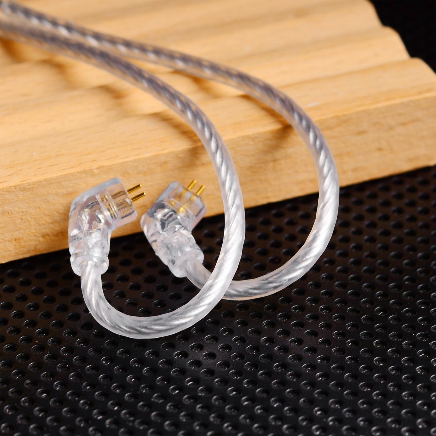 Clear, flexible IEM cable from THE VOLTRAY VAULT, featuring two connectors and a braided design on a textured surface.